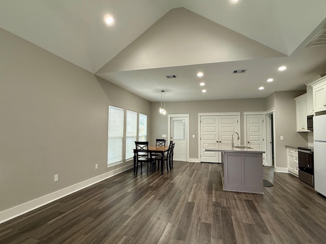 kitchen with hanging light fixtures, electric range, an island with sink, white cabinets, and dark hardwood / wood-style flooring