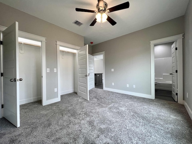 unfurnished bedroom featuring ceiling fan, dark carpet, and ensuite bath