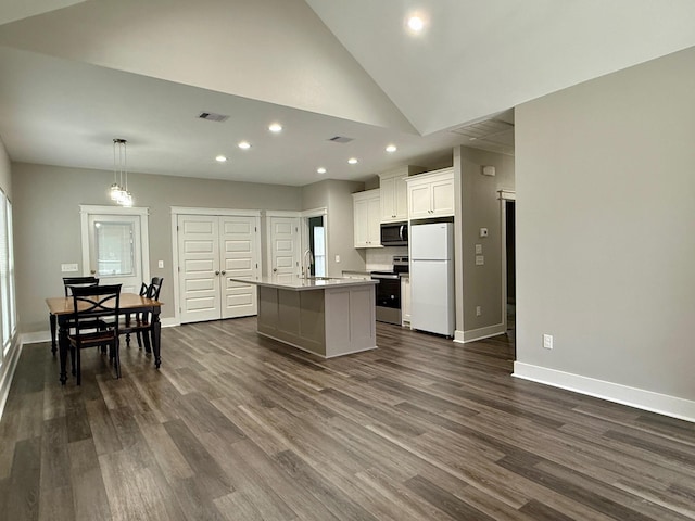 kitchen with stainless steel electric stove, decorative light fixtures, an island with sink, white cabinetry, and white refrigerator