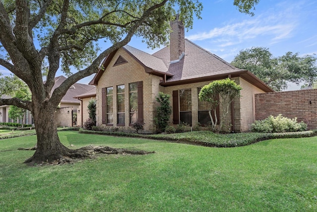 rear view of property featuring a chimney, brick siding, and a yard