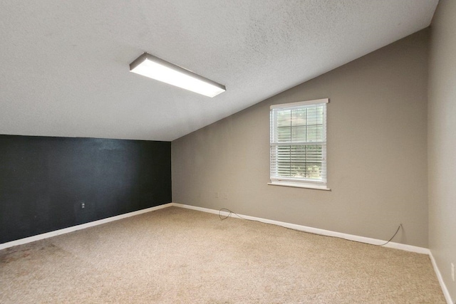 additional living space with a textured ceiling, lofted ceiling, and carpet floors