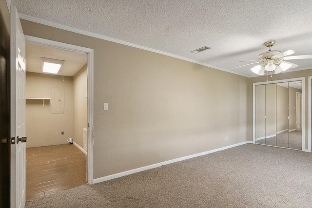 unfurnished bedroom with ornamental molding, a textured ceiling, light colored carpet, ceiling fan, and a closet