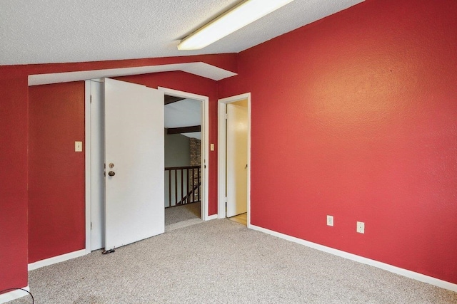 carpeted empty room with lofted ceiling and a textured ceiling