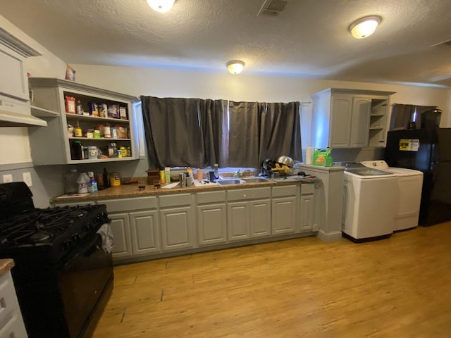 3600 Main Ave, Groves, TX 77619 - kitchen with gas stove, open shelves, washing machine and dryer, light wood-style flooring, and a textured ceiling