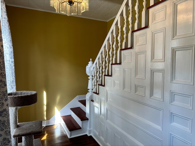 stairs featuring hardwood / wood-style flooring, crown molding, and a notable chandelier