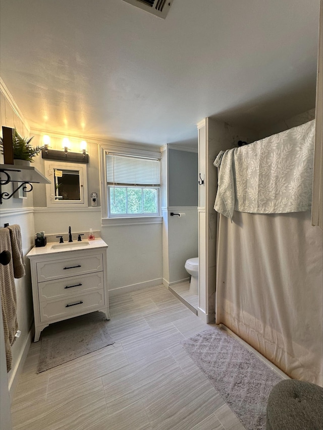 bathroom with vanity, toilet, and ornamental molding