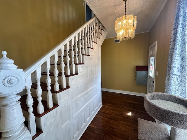 staircase with wood-type flooring, an inviting chandelier, and ornamental molding