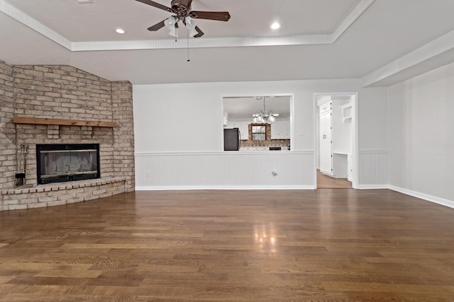 unfurnished living room with lofted ceiling, dark hardwood / wood-style floors, ceiling fan with notable chandelier, and a brick fireplace