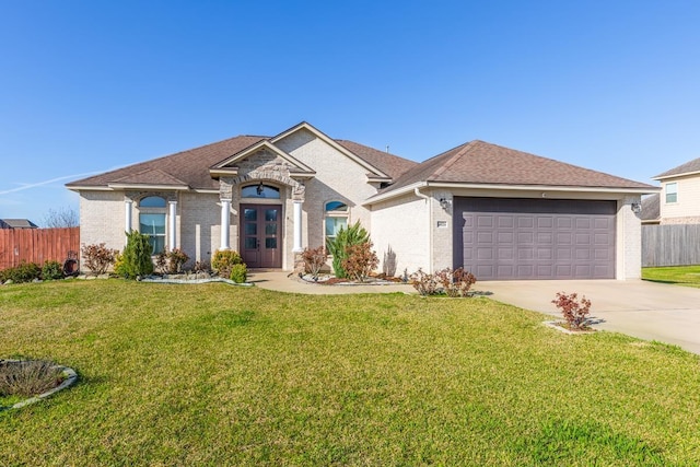 view of front of property with brick siding, an attached garage, a front yard, fence, and driveway