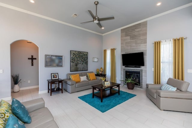 living area featuring arched walkways, ornamental molding, visible vents, and a ceiling fan