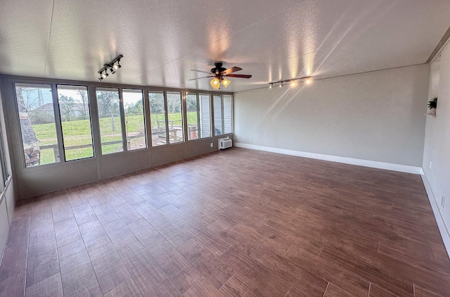 unfurnished sunroom with ceiling fan, a wall mounted air conditioner, rail lighting, and a wealth of natural light