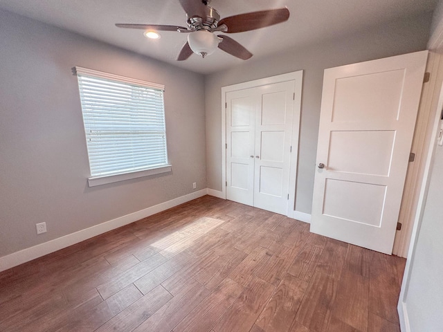 unfurnished bedroom with a closet, ceiling fan, baseboards, and wood finished floors