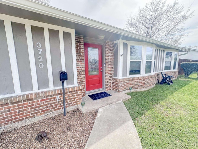 entrance to property with brick siding and a lawn