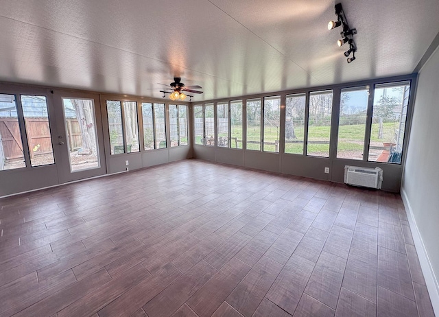 unfurnished sunroom with ceiling fan, track lighting, and a wall mounted air conditioner