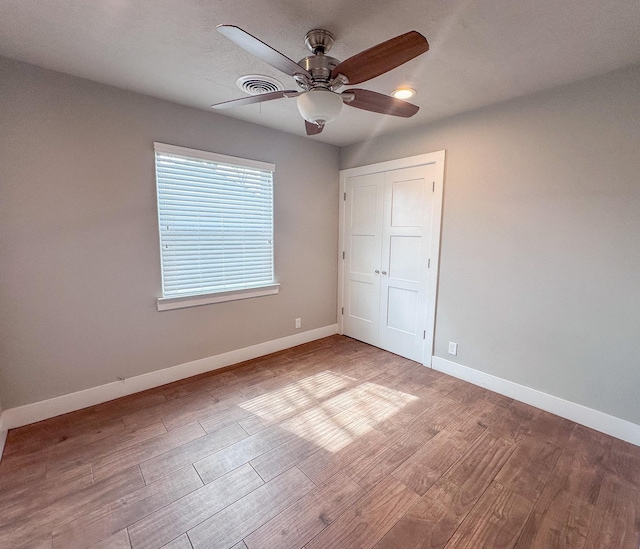 unfurnished bedroom featuring a closet, visible vents, light wood-style floors, a ceiling fan, and baseboards