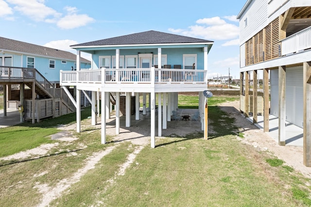 back of house with roof with shingles, a yard, stairway, a carport, and driveway