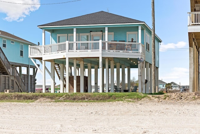 rear view of property featuring a shingled roof, stairs, a porch, and a carport