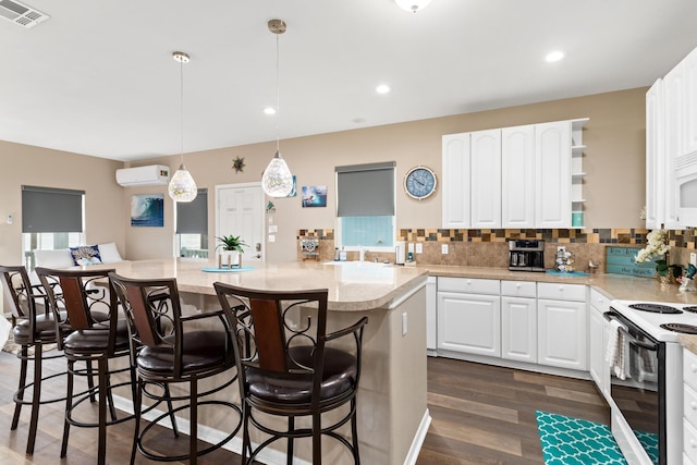 kitchen with electric range, a kitchen island, visible vents, a kitchen breakfast bar, and a wall mounted AC