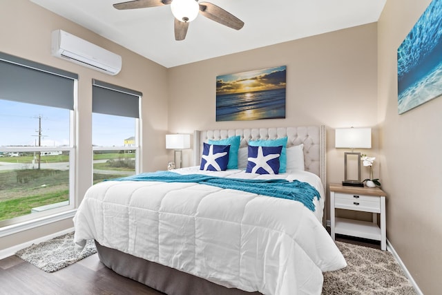bedroom with ceiling fan, baseboards, an AC wall unit, and wood finished floors
