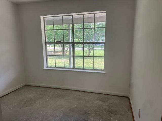 unfurnished room featuring baseboards and unfinished concrete floors