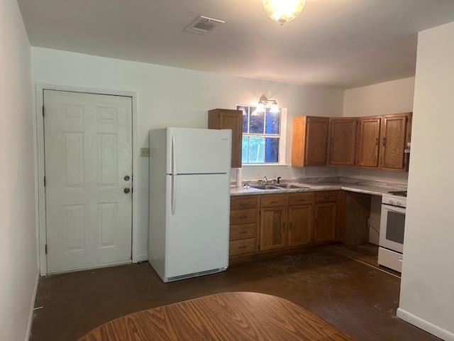 kitchen featuring visible vents, white appliances, light countertops, brown cabinets, and a sink