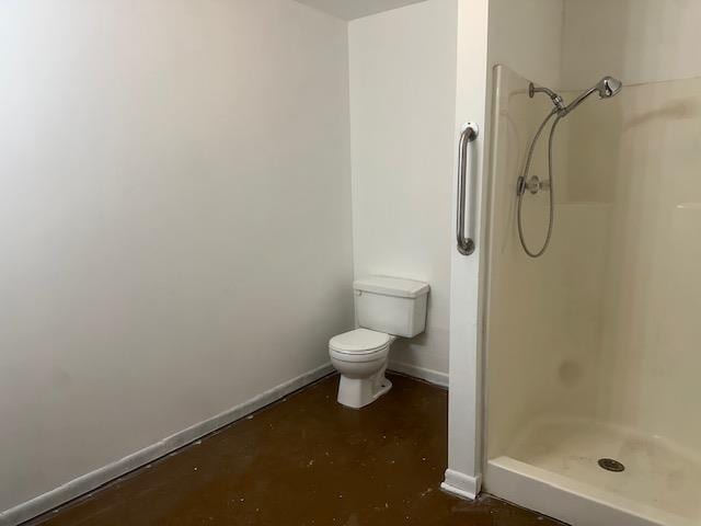 bathroom with baseboards, concrete flooring, toilet, and a shower stall