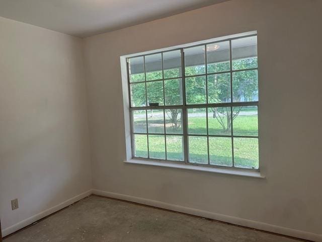 spare room featuring baseboards, concrete floors, and a wealth of natural light