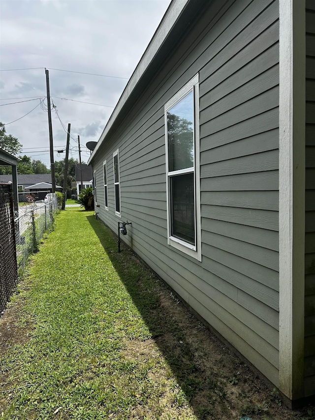 view of side of home with fence and a yard
