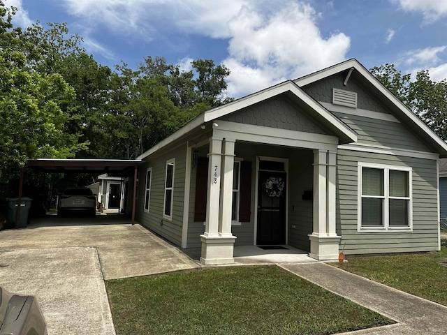 bungalow-style house with a porch, driveway, a front lawn, and a carport