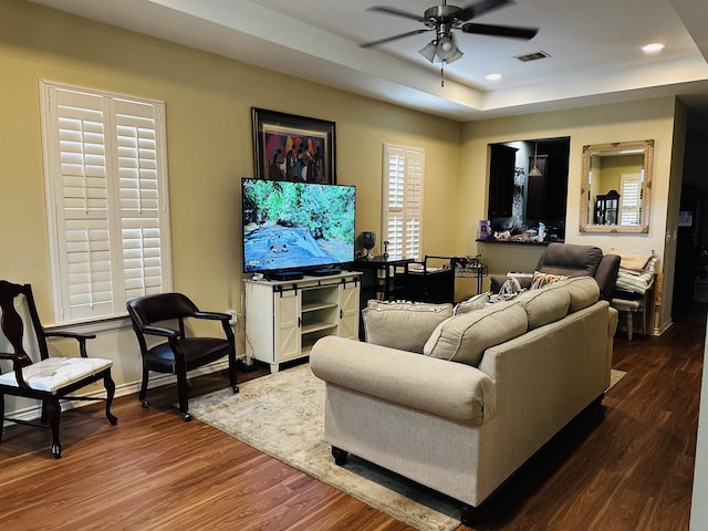living room featuring a raised ceiling, a ceiling fan, recessed lighting, dark wood-type flooring, and visible vents