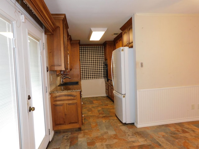 kitchen with light stone countertops, sink, and white refrigerator