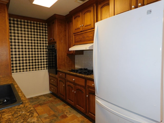 kitchen with black appliances, backsplash, sink, and dark stone counters