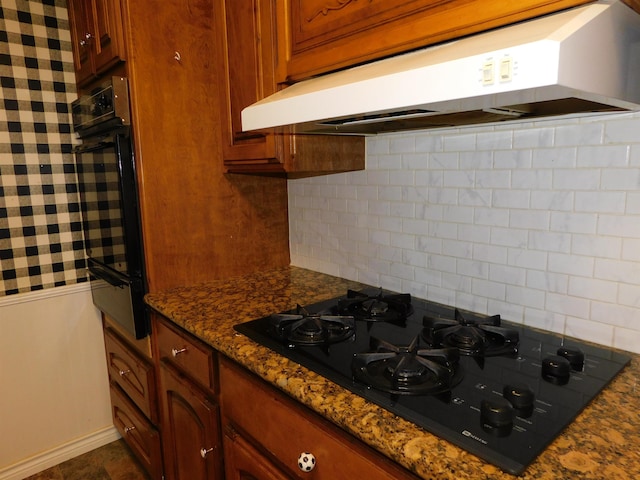 kitchen featuring decorative backsplash, dark stone countertops, and black appliances