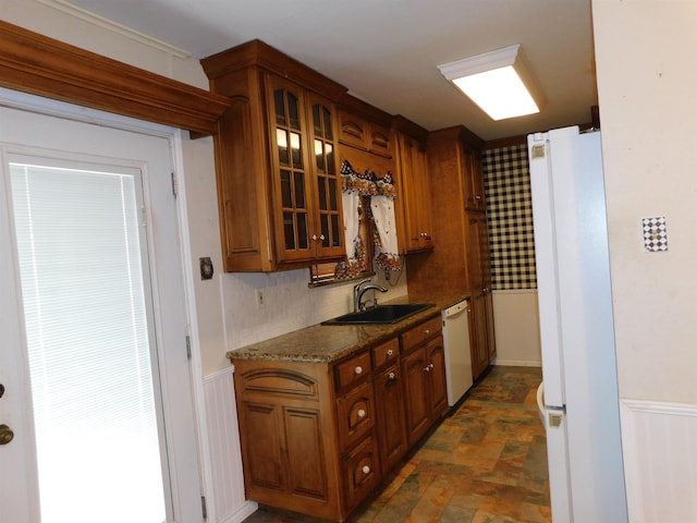 kitchen with backsplash, sink, dark stone counters, and white appliances