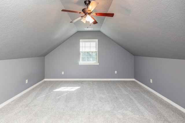 additional living space with a textured ceiling, ceiling fan, carpet, and lofted ceiling