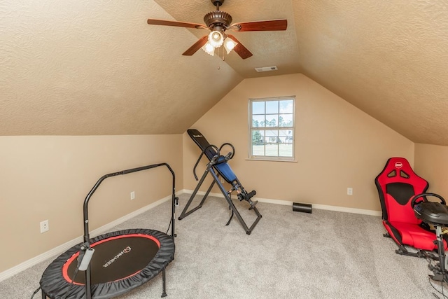 exercise area featuring ceiling fan, a textured ceiling, light carpet, and vaulted ceiling