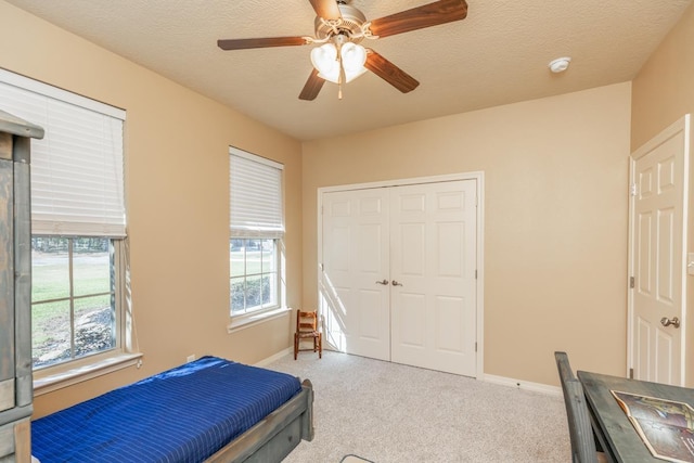 carpeted bedroom with multiple windows, a textured ceiling, a closet, and ceiling fan