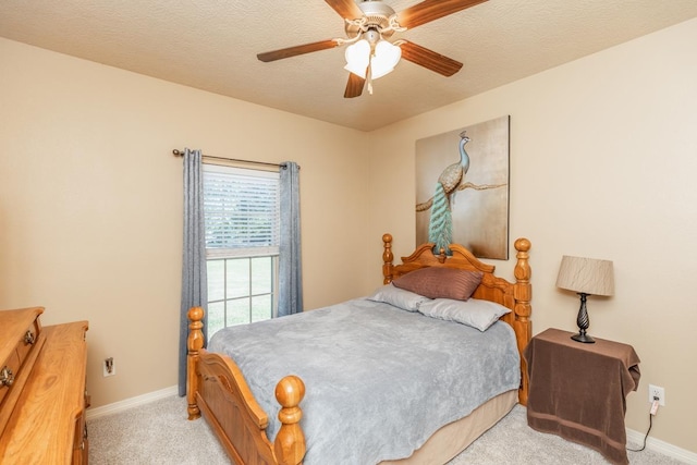 bedroom with ceiling fan, light colored carpet, and a textured ceiling