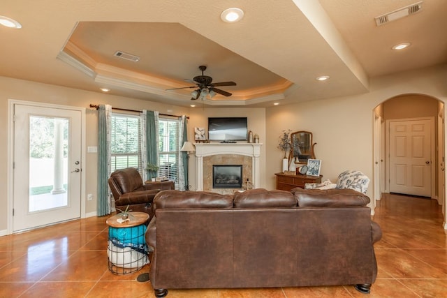 living room featuring ceiling fan, light tile patterned floors, ornamental molding, and a tray ceiling