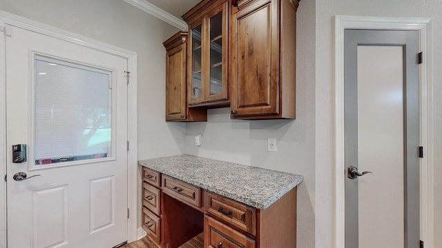 1405 Turner Dr, Bridge City, TX 77611 - kitchen featuring ornamental molding, glass insert cabinets, brown cabinets, and light stone countertops