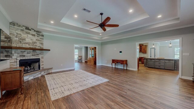 1405 Turner Dr, Bridge City, TX 77611 - living room with a tray ceiling, ceiling fan, wood finished floors, a stone fireplace, and recessed lighting