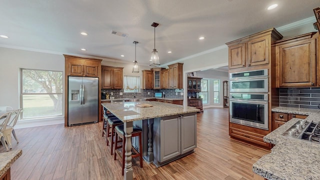 1405 Turner Dr, Bridge City, TX 77611 - kitchen with appliances with stainless steel finishes, brown cabinets, ornamental molding, a kitchen island, and tasteful backsplash