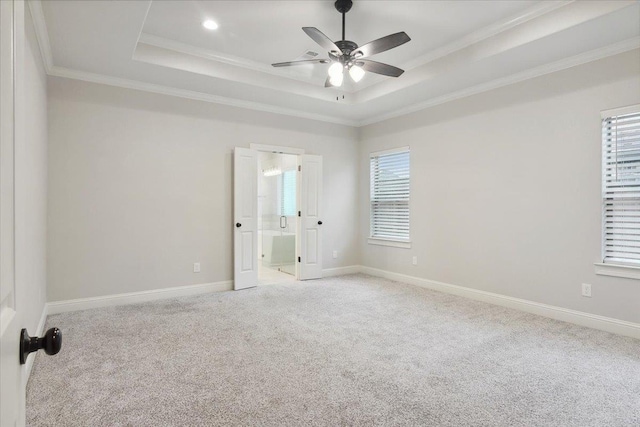 empty room featuring ornamental molding, a tray ceiling, ceiling fan, and light colored carpet