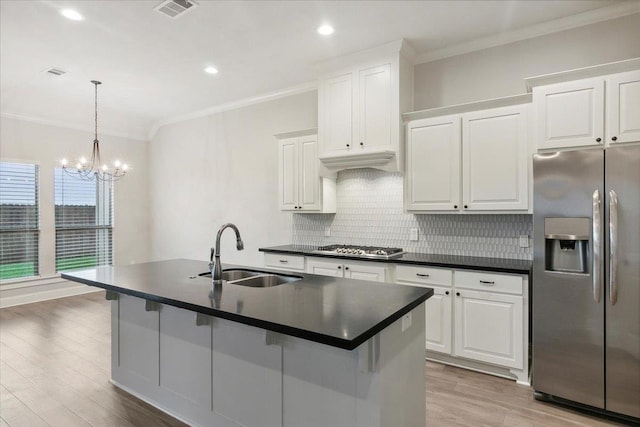 kitchen with appliances with stainless steel finishes, an island with sink, white cabinetry, and sink