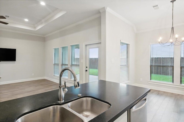 kitchen with sink, hanging light fixtures, hardwood / wood-style floors, a tray ceiling, and ornamental molding