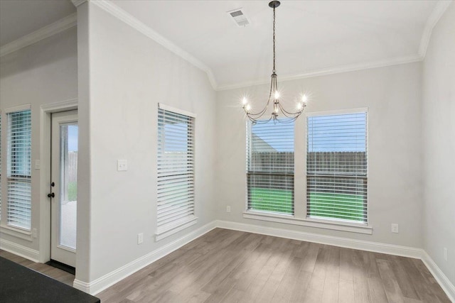 unfurnished dining area featuring hardwood / wood-style flooring, crown molding, and an inviting chandelier