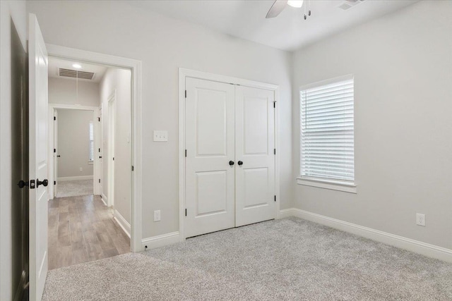 unfurnished bedroom featuring light carpet, a closet, and ceiling fan