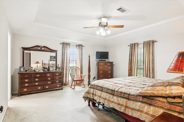 bedroom featuring crown molding, ceiling fan, a tray ceiling, and light carpet