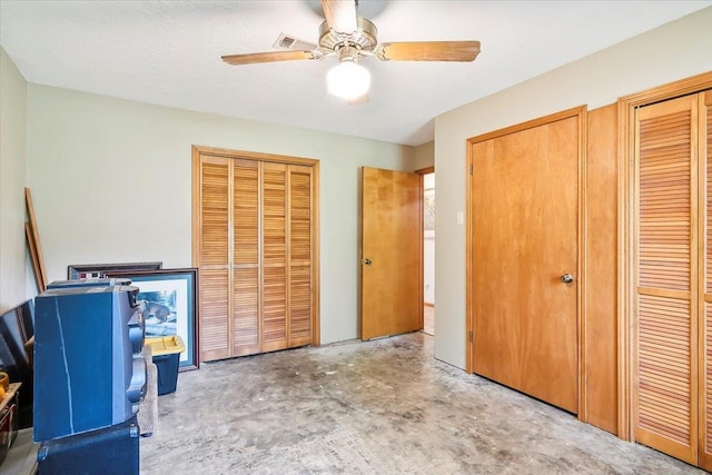 unfurnished bedroom featuring concrete flooring, two closets, and ceiling fan