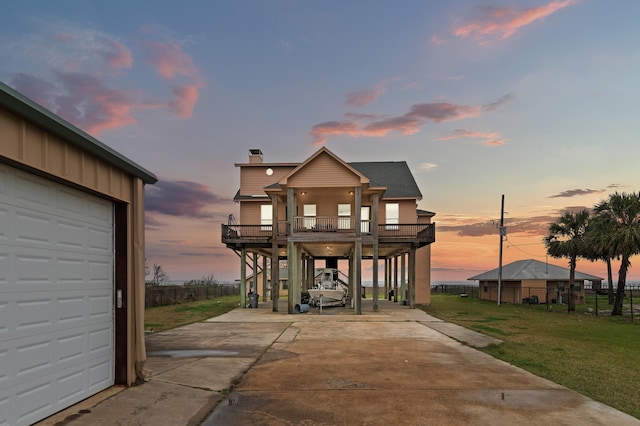 beach home with a balcony, a garage, stairs, driveway, and a front lawn